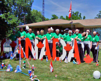 Some of the Optimists Alumni in front of Helen Young's house (Port Dover, 2011)
Here is the photo of the band in front of my home that I promised you.  Thanks for having the band play "The Maple Leaf Forever" before you marched off. You might be interested to know that my oldest son made the big CANADA sign in 2000, He died in 2002, so it's put up each July 1st in his special honour. Hope you'll return next year, and I hope to decorate our home again, so please drop by. Helen
Keywords: 2011