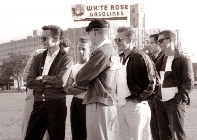 Optimists Colin Hedworth (left), Henry Beben (hiding behind Colin), Dave Hanks (white t-shirt), Warren Mills (in Cavaliers jacket), John Carrie (right end) (watching Del practice on the waterfront, 1960)
Photo by Don Daber
Keywords: 1960